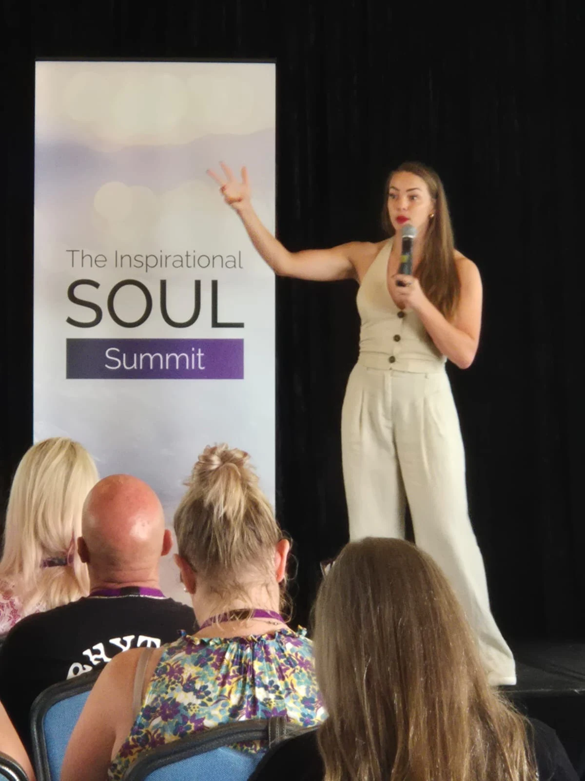 Danya speaking with a microphone in a live room