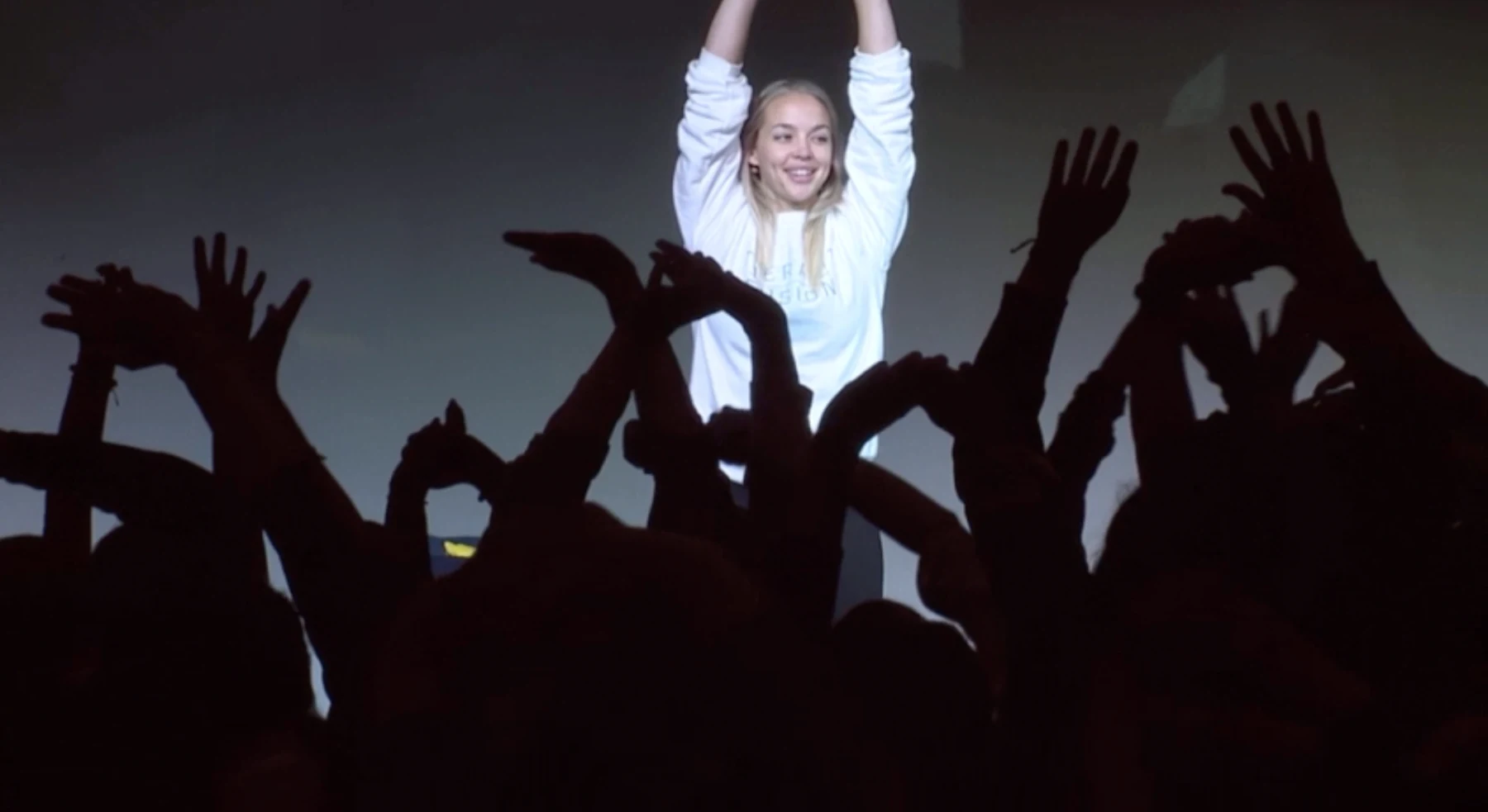 Danya leading a live audience in a high-energy room